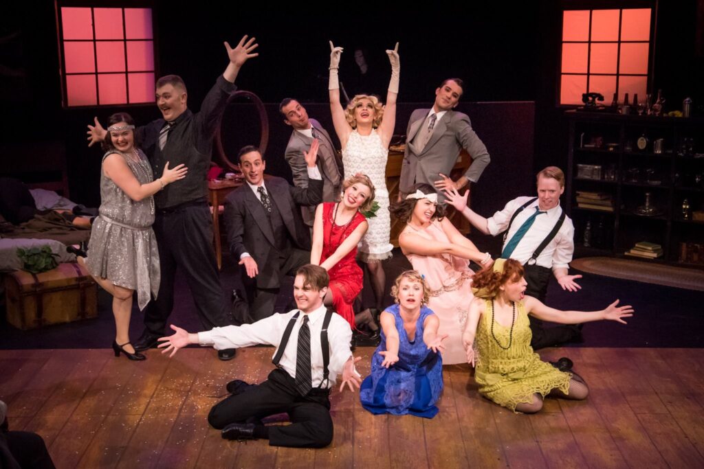 Actors in the cast of the Wild Party pose at the end of a musical number. The actors are all dressed in 1920s period costumes.